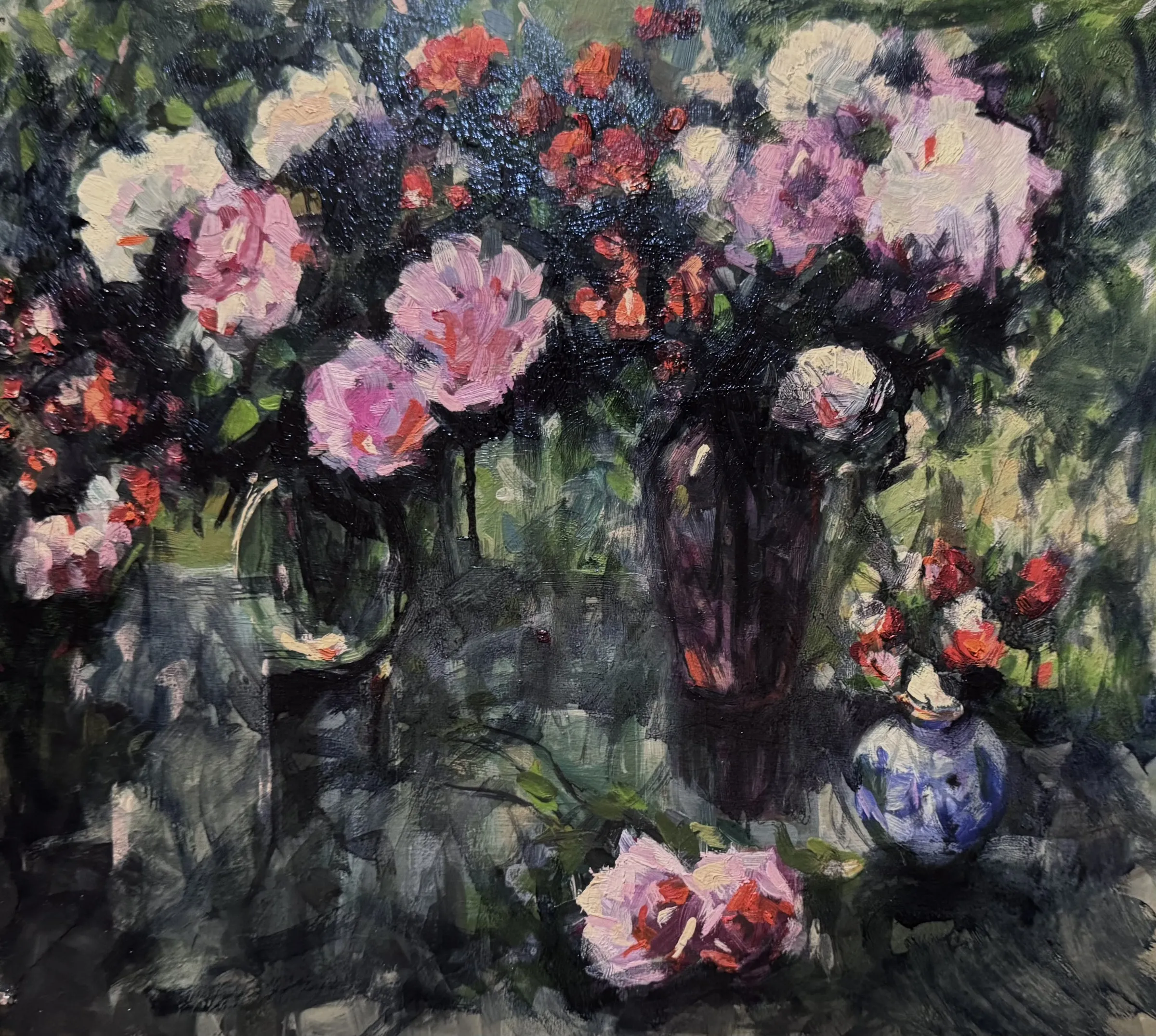Pink roses in several vases on a dark green ground